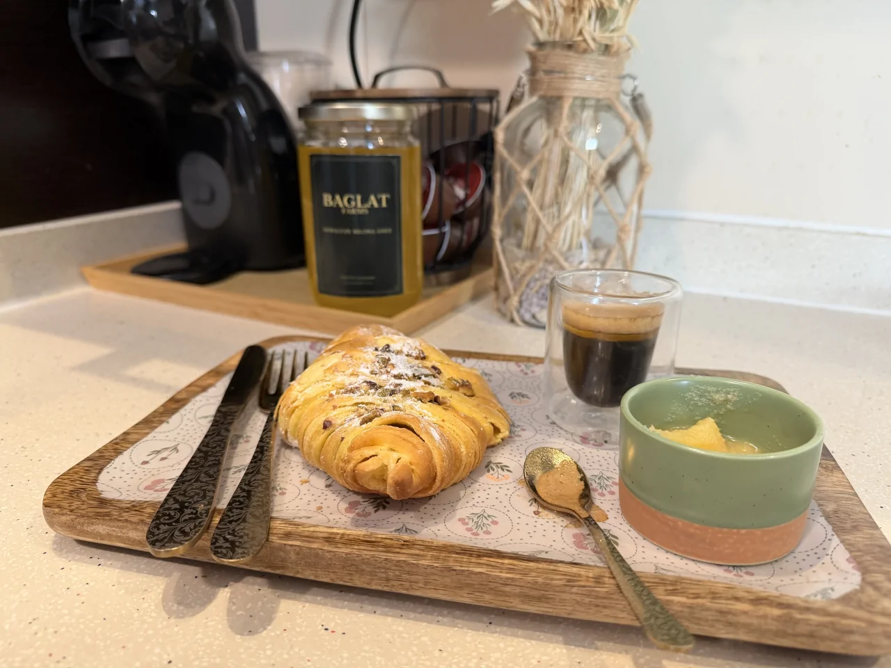 Black coffee and a bowl of ghee beside a Baglat Farms ghee jar and pastry